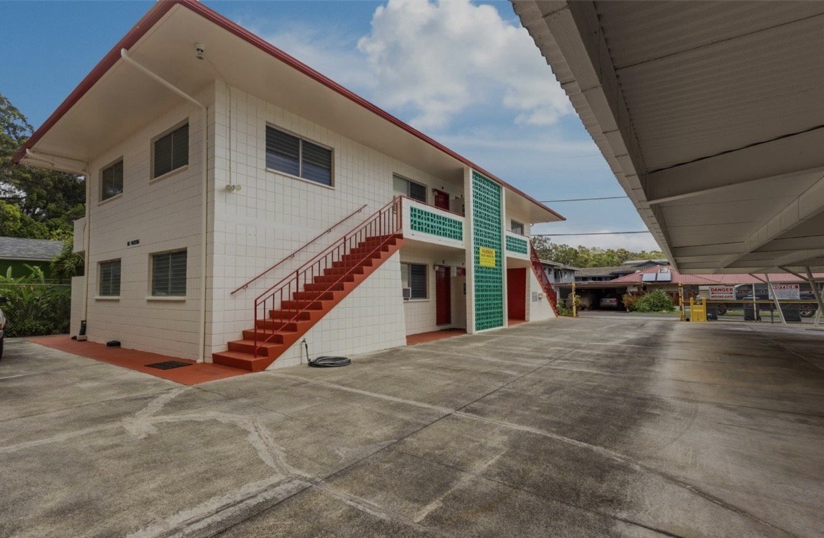 A white building with a red staircase in front.